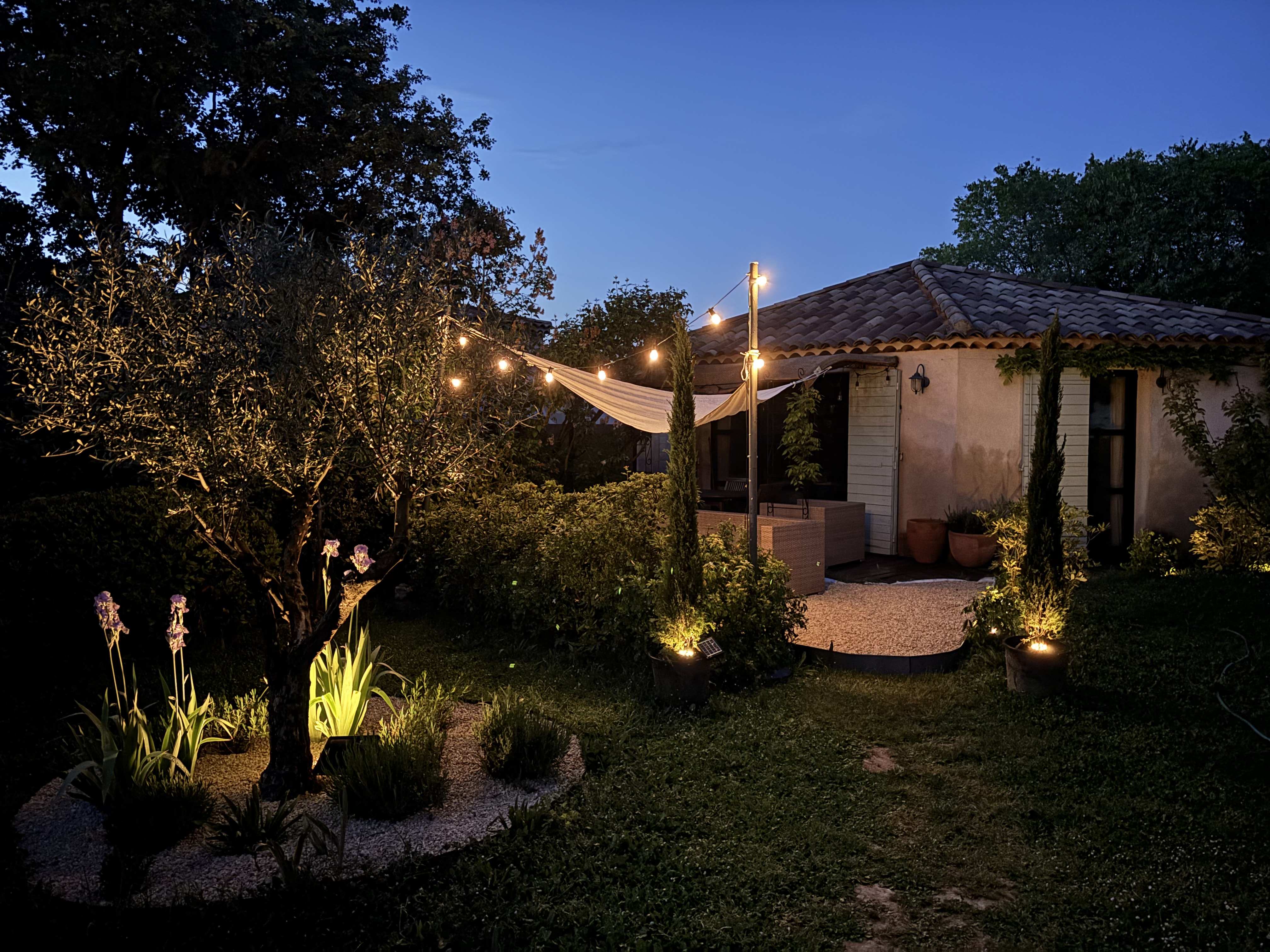 La Tanière — jardin à la golden hour avec guirlandes lumineuses